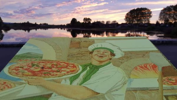 Carton Pizz'Popotte devant un coucher de soleil sur le lac